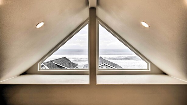 Ein dreieckiges Oberlicht mit Blick auf das Meer und Gebäude darunter.