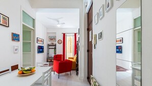 A modern living room with a dining area, featuring a white table, red chairs, and a sofa.