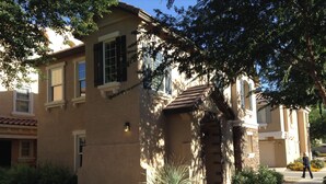 A residential building with a brick facade, multiple windows, and a small porch. - Beautiful centrally located townhome in The Gardens, Gilbert (Gilbert)