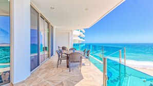 A balcony with a table and chairs, overlooking a beach and the ocean. - Esmeralda Beach Resort 2 Bedrooms Condo B 502 (Puerto Peñasco)