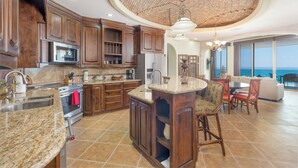 A spacious kitchen with granite countertops, wooden cabinets, and a large island. - Esmeralda Beach Resort 2 Bedrooms Condo B 502 (Puerto Peñasco)