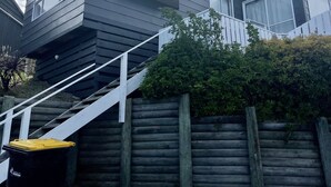 A two-story house with a balcony, a wooden fence, and a staircase leading to the entrance. - Soothing Sounds (Otago)