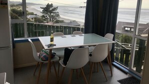 A room with a table and chairs, a bottle, and a bag on the table. - Soothing Sounds (Otago)
