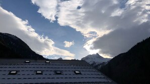 A mountain landscape with a building featuring a sloped roof and multiple skylights. - 3-room cabin apartment, south-facing balcony, 5 pers., private parking (Les Contamines-Montjoie)
