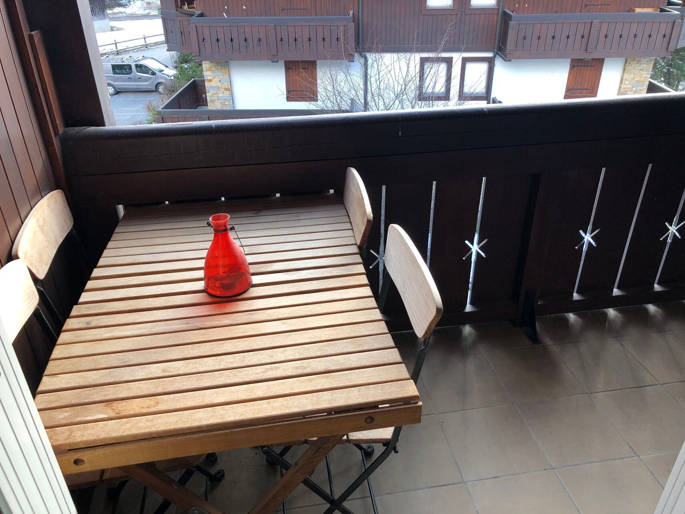 Un tavolo di legno con quattro sedie su un balcone che offre vista sugli edifici.