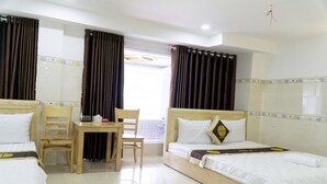 A hotel room with two beds, a wooden desk, chairs, and a window with curtains. - Dai An Binh Tan Hotel (Ho Chi Minh City)