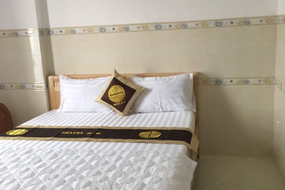 A hotel room with a bed, pillows, and a bedspread with a logo.