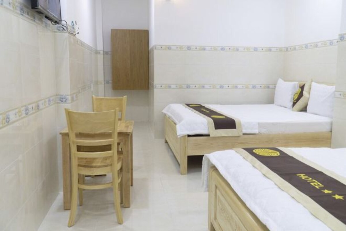 A hotel room with two beds, a wooden chair, and a small table.