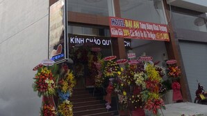 A multi-story building with a green and white facade, large windows, and a sign advertising a hotel. - Dai An Binh Tan Hotel (Ho Chi Minh City)