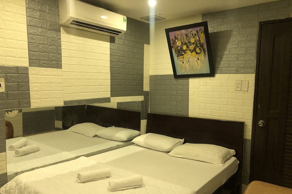 Une chambre d’hôtel avec deux lits, du linge de lit blanc, un tableau au mur et une porte.