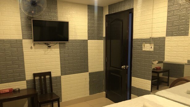 Ein Hotelzimmer mit Bett, Schreibtisch, Stuhl, Wandfernseher und einer Tür.