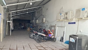Un espacio interior cubierto con suelo de baldosas, una motocicleta y un refrigerador.