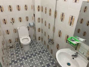 A bathroom with a toilet, a sink, and a shower. The floor has a patterned tile design.