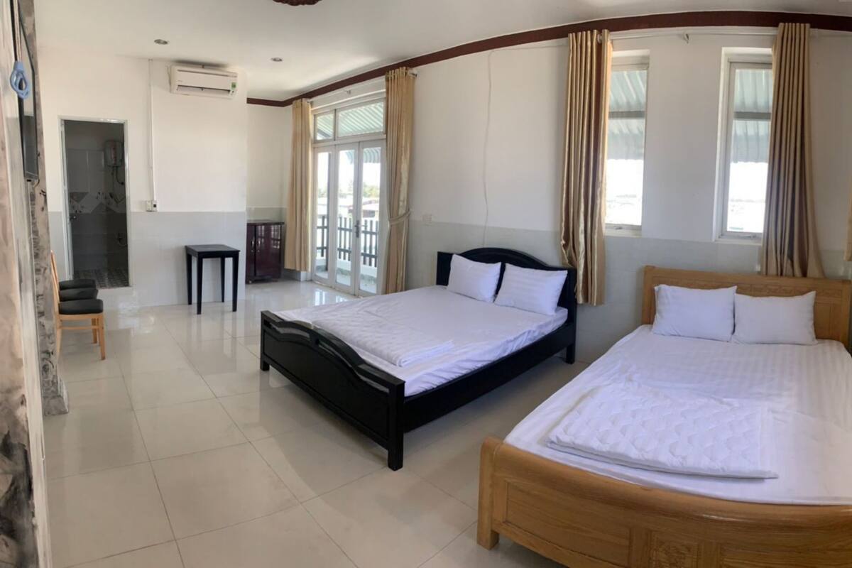 A hotel room with two beds, a small table, and a shower area.