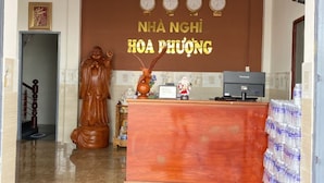 Un área de recepción con un escritorio de madera, una estatua de Buda y un reloj de pared.