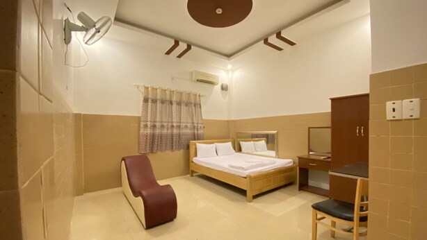 Una habitación de hotel con una cama, una silla, un escritorio y un espejo.