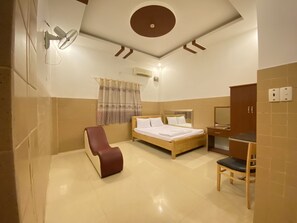 A hotel room with a bed, a chair, a desk, and a mirror.