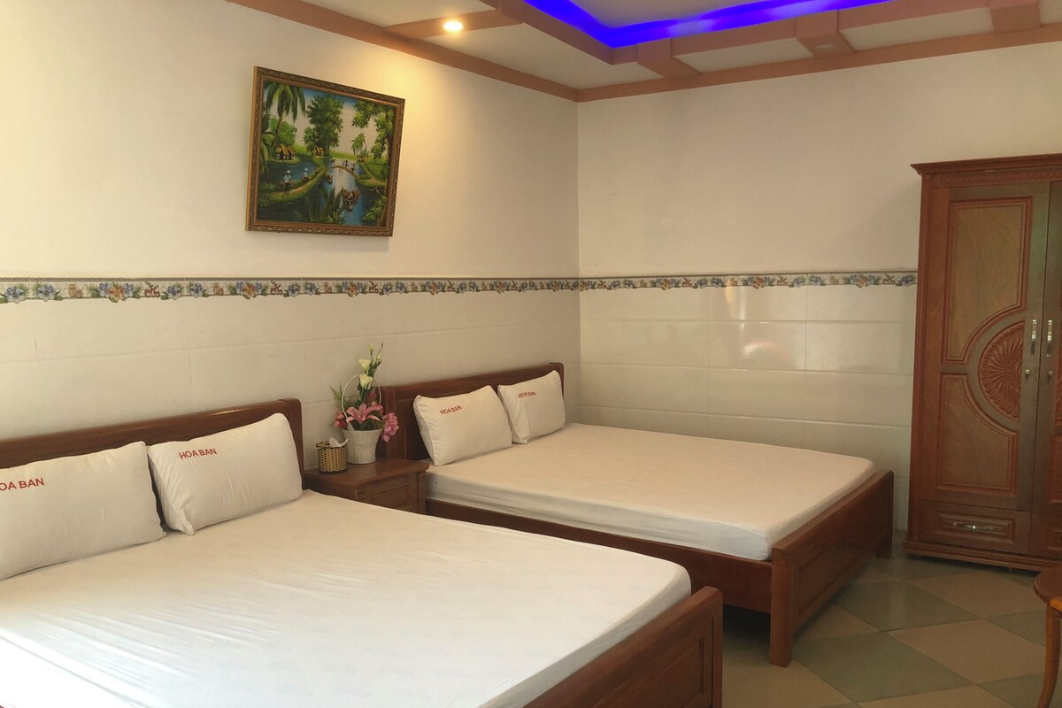 Habitación de hotel con dos camas individuales, un armario de madera, un cuadro en la pared y suelo de baldosas.