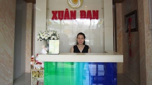 Una mesa de recepción con un cartel que dice "XUÂN DAN" y cuatro relojes encima.