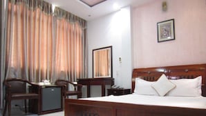 Una habitación de hotel con una cama de madera, un escritorio, una silla y un refrigerador pequeño.