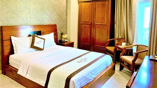 Ein Hotelzimmer mit einem großen Bett, einem Holzschrank, einem Schreibtisch und einem Stuhl.