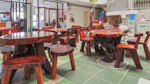 A restaurant with wooden tables and chairs, a tiled floor, and a counter with a water dispenser. - View Mansion (Chonburi)