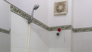 A bathroom with a white sink, a toilet, a shower with a handheld showerhead, and a waste bin. - Ngoc Trinh Hotel Binh Tan (Ho Chi Minh City)