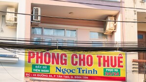 A building with a sign for 'Phong Cho Thu' and 'Ngoc Trinh' motel, featuring a 24/7 service, and a visible entrance with a gated door. - Ngoc Trinh Hotel Binh Tan (Ho Chi Minh City)