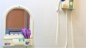 Baño con secador de manos, barra para toallas y un espejo pequeño con ventana.