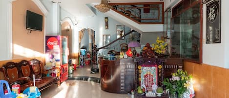 A hotel lobby with a reception desk, a staircase, and a seating area with chairs.