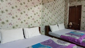 A room with two beds, floral wallpaper, a wooden wardrobe, and a bedside table with a lamp. - Khanh Vy Hotel Binh Tan (Ho Chi Minh City)