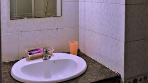 A bathroom with a white sink, a mirror, and a small basket with toiletries. - Khanh Vy Hotel Binh Tan (Ho Chi Minh City)
