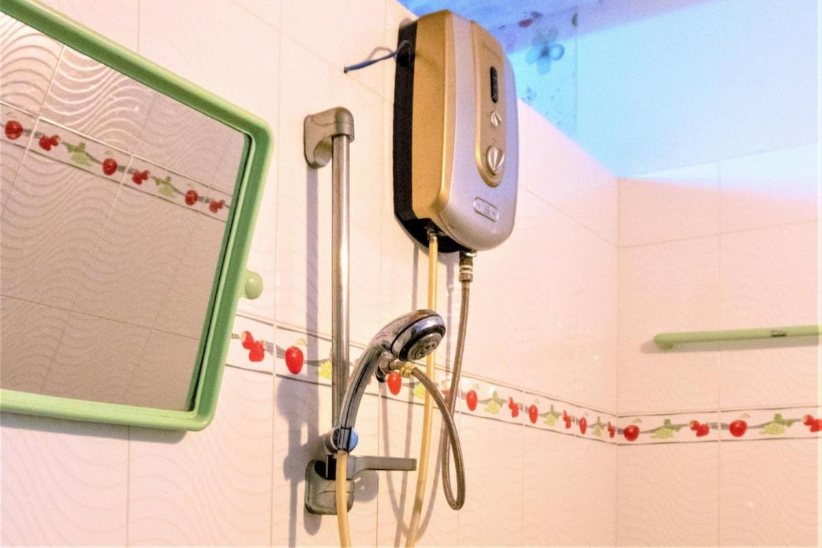 A bathroom with a shower, a handheld showerhead, and a wall-mounted control panel.
