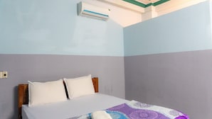 Ein Zimmer mit einem Bett, zwei Kissen, einer Decke und einer Klimaanlage an der Wand.