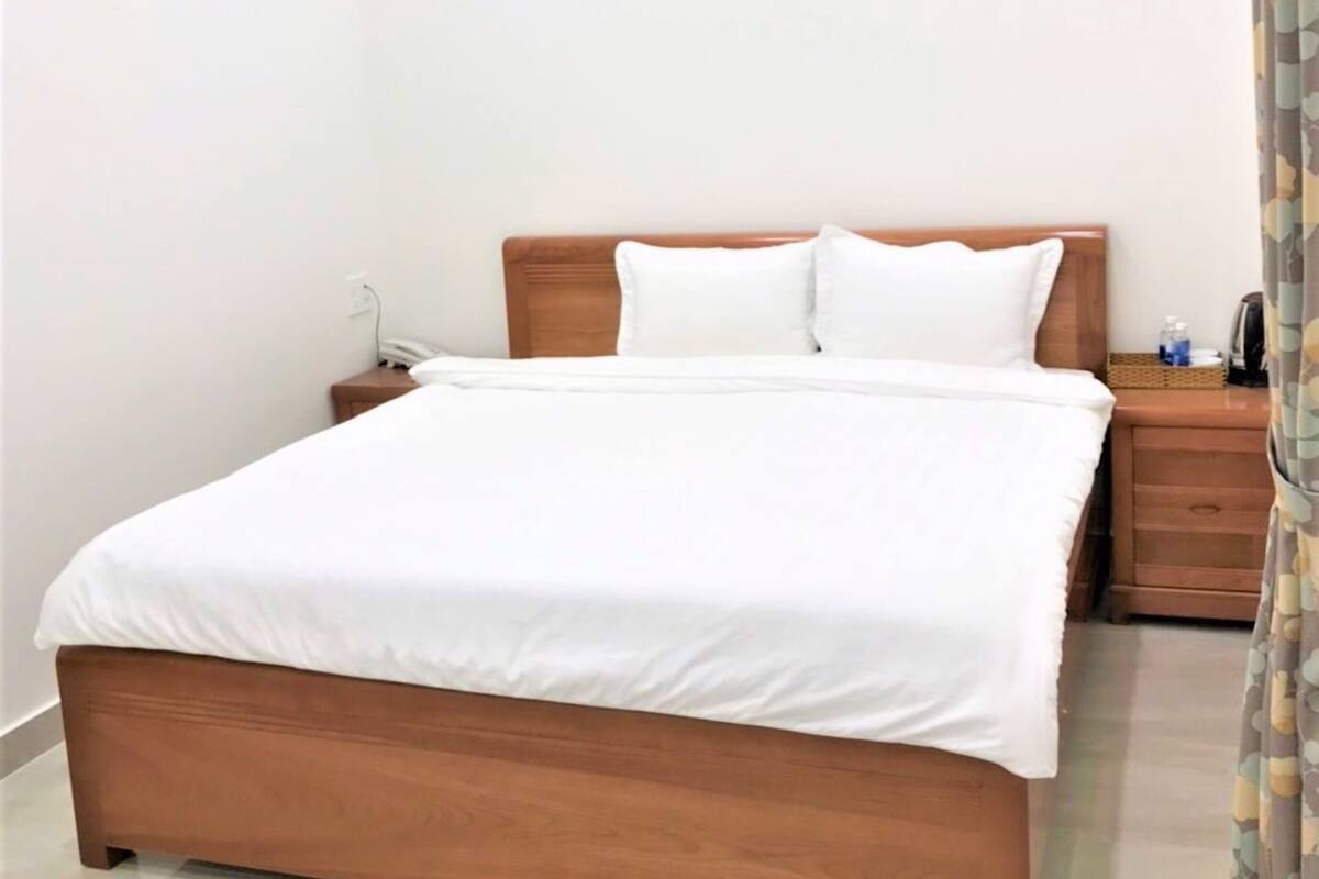 A neatly made bed with a wooden headboard and white bedding in a hotel room.