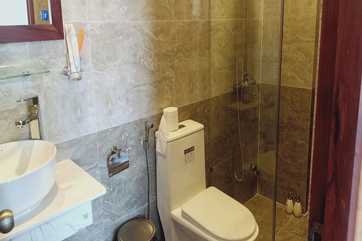 Un baño con lavamanos blanco, inodoro y cabina de ducha con puerta de cristal.