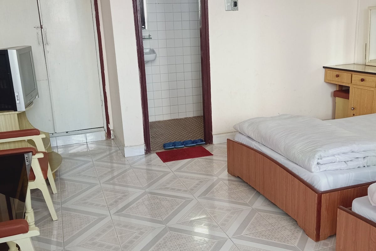 A hotel room with a bed, a desk with a chair, a television, and a bathroom with a toilet and sink.