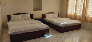 A hotel room with two single beds, a small bedside table, a mirror, and a window with curtains. - Thuan Lam Hotel (Lam Vien - Da Lat)