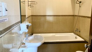 A bathroom with a bathtub, a sink, and a toilet. There are toiletries on the sink counter. - Nhat Huy Hotel (Xuan Huong - Da Lat)