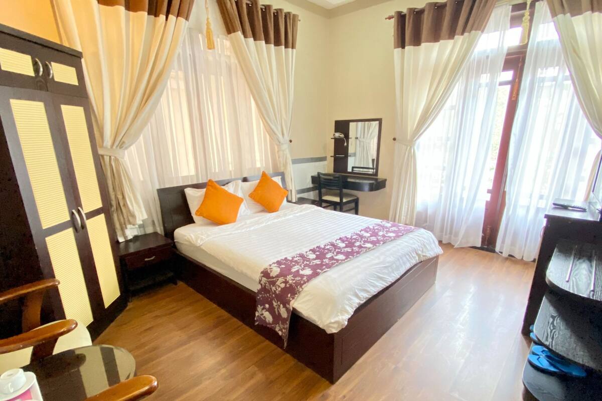 Une chambre d’hôtel avec un lit, un bureau, une chaise et un miroir.