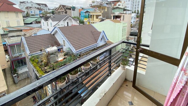 A balcony with potted plants and a view of a residential area with various buildings. - Sao Mai Tim Hotel (Xuan Huong - Da Lat)