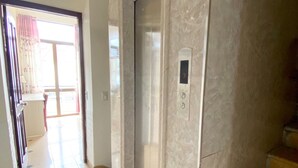 An elevator with a digital display showing the number 3, a tiled floor, and a door leading to a balcony with a view. - Sao Mai Tim Hotel (Xuan Huong - Da Lat)