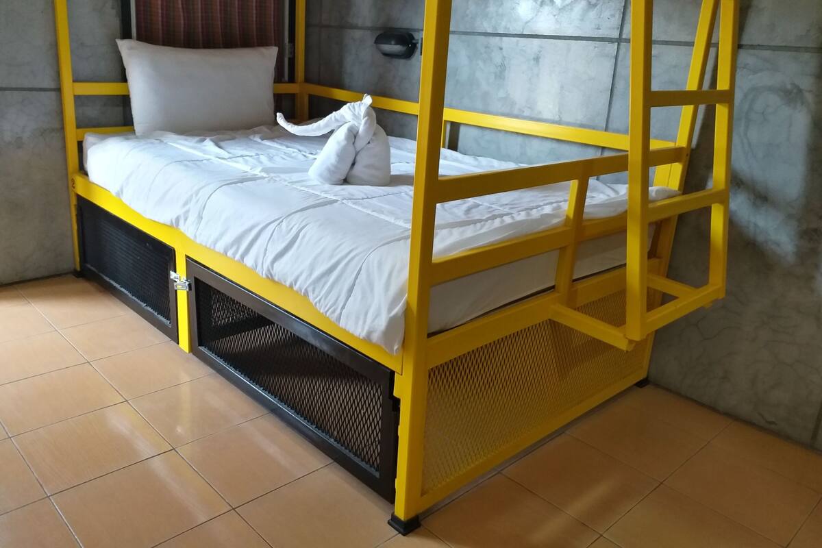 Uma cama beliche com estrutura amarela e roupa de cama branca.