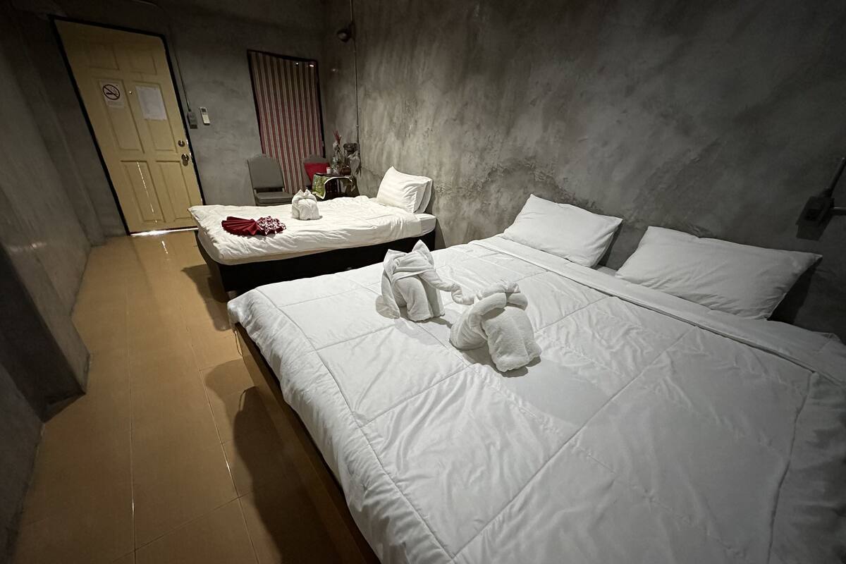 Quarto de hotel com duas camas, uma cadeira, uma mesa e uma porta com o aviso de proibido fumar.