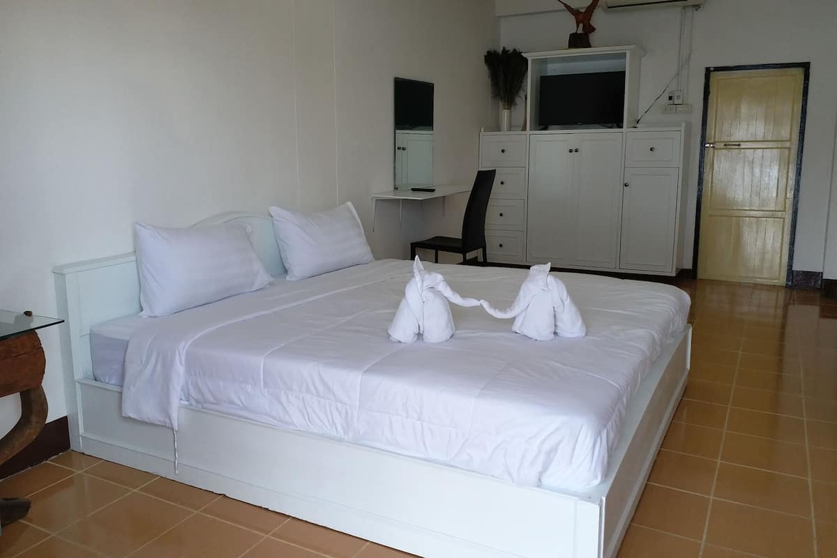 Quarto de hotel com cama, escrivaninha, cadeira, guarda-roupa e ar condicionado.