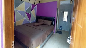 Een slaapkamer met een bed, een geometrisch wandontwerp en een deur naar een andere kamer.