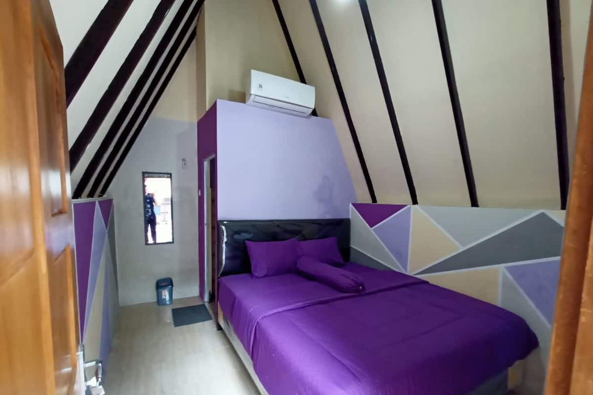 Een slaapkamer met een bed, een airconditioning, een raam en een wand met een geometrisch patroon.