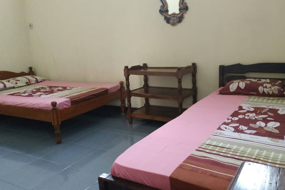 A room with two wooden beds, each with a pink bedspread and floral pillows.