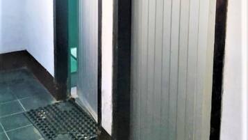 A narrow hallway with a door on the right and a green object on the left.
