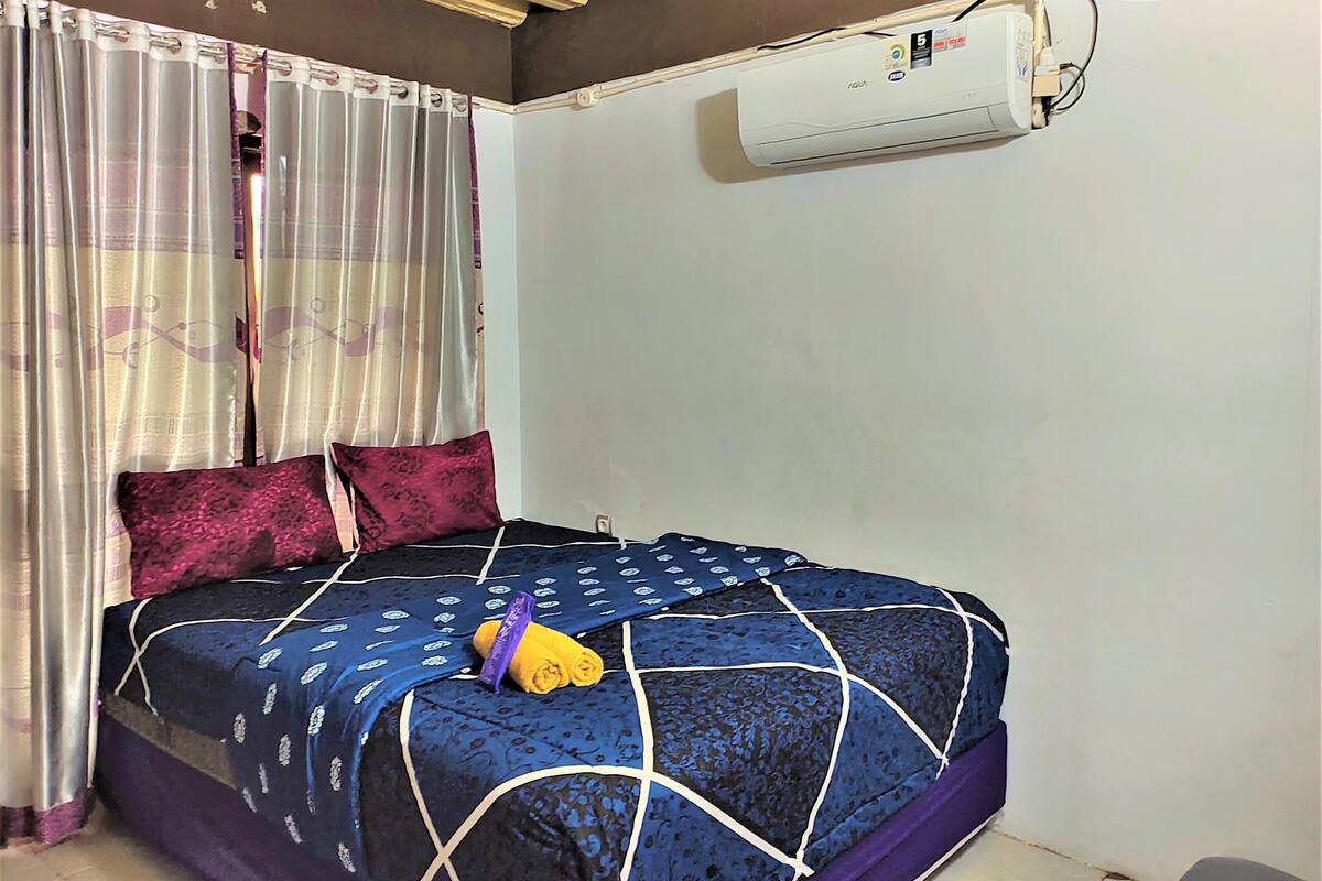 Une chambre à coucher avec un lit, des rideaux et un appareil de climatisation.